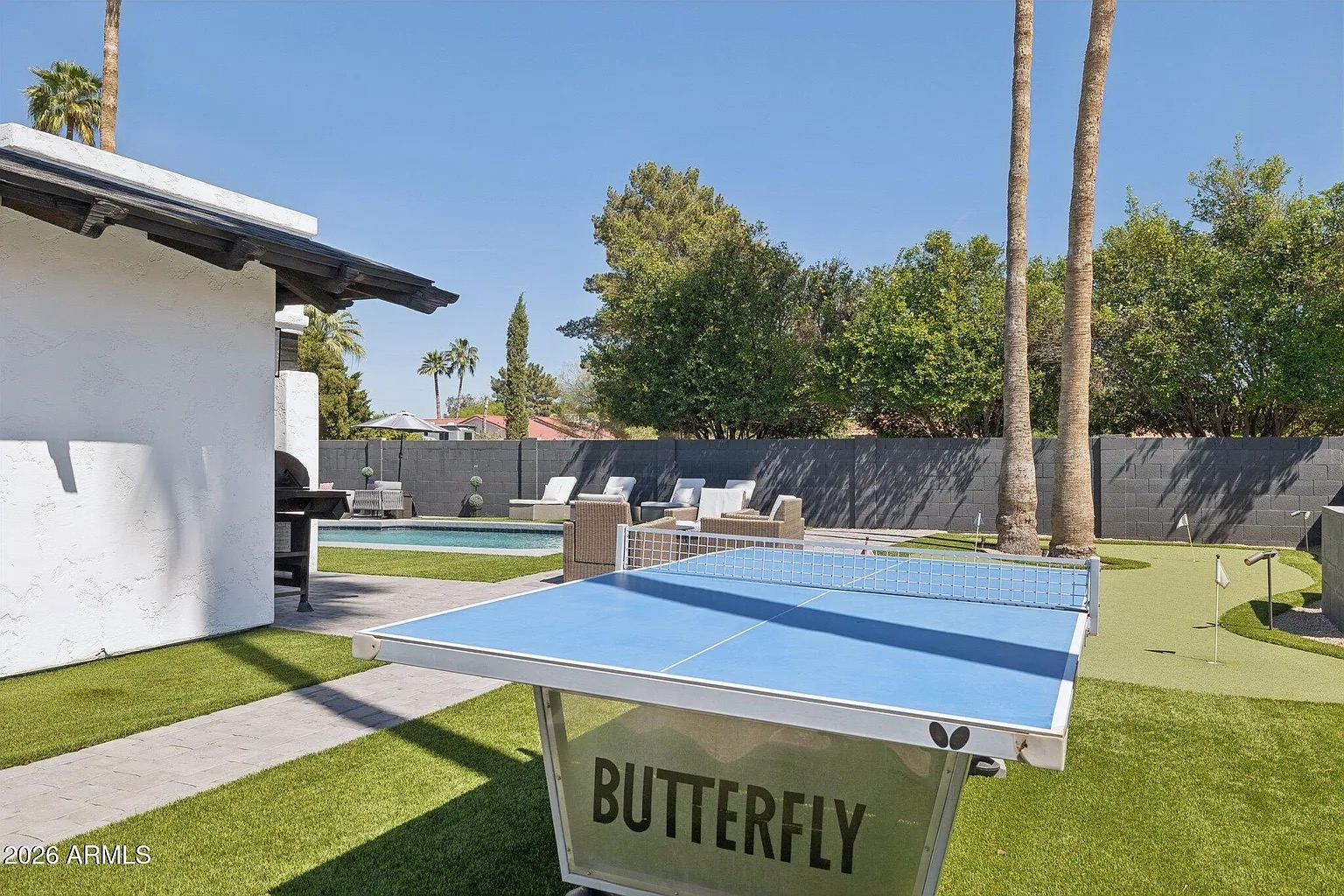 Butterfly ping-pong table on turf between pool and putting green